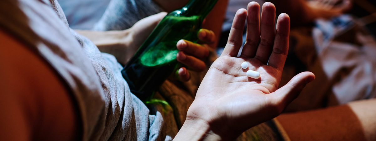 Eine junge Person mischt Alkohol mit Medikamenten.