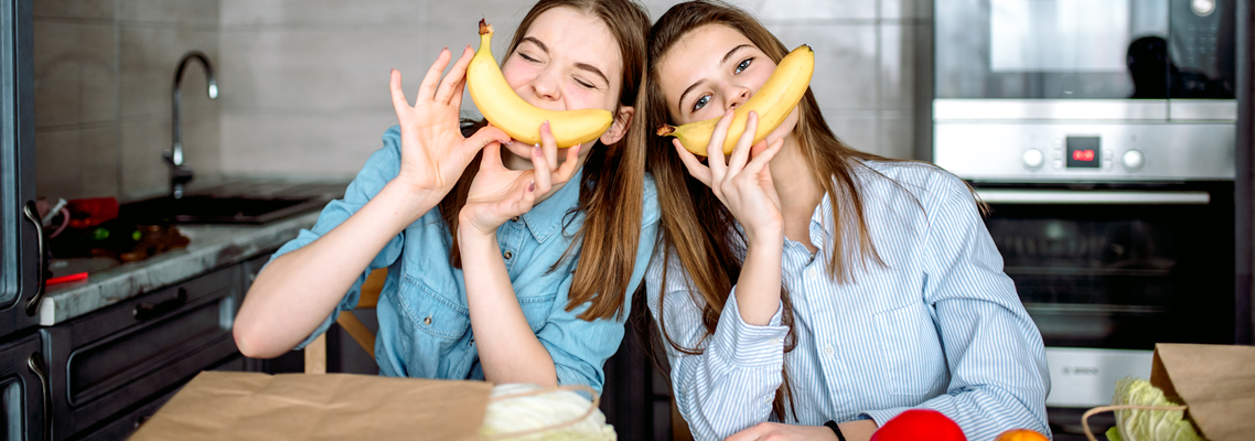 Zwei junge Frauen zeigen ein Lächeln mit einer Banane