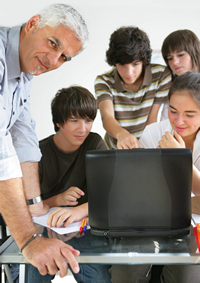 Lehrer mit Jugendlichen vor einem Computer